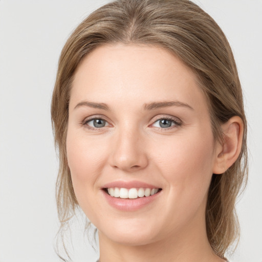 Joyful white young-adult female with medium  brown hair and grey eyes