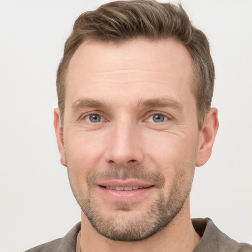 Joyful white young-adult male with short  brown hair and grey eyes