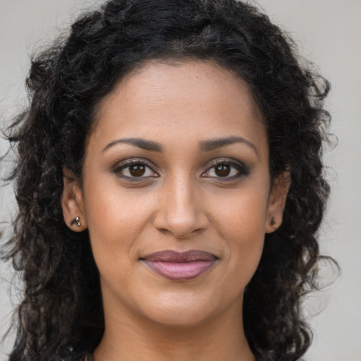 Joyful black young-adult female with long  brown hair and brown eyes