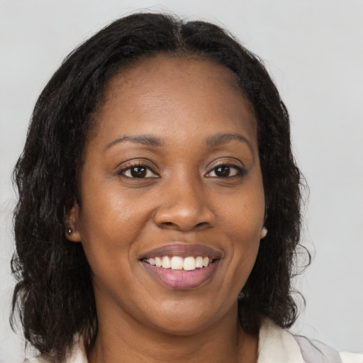 Joyful black young-adult female with long  brown hair and brown eyes