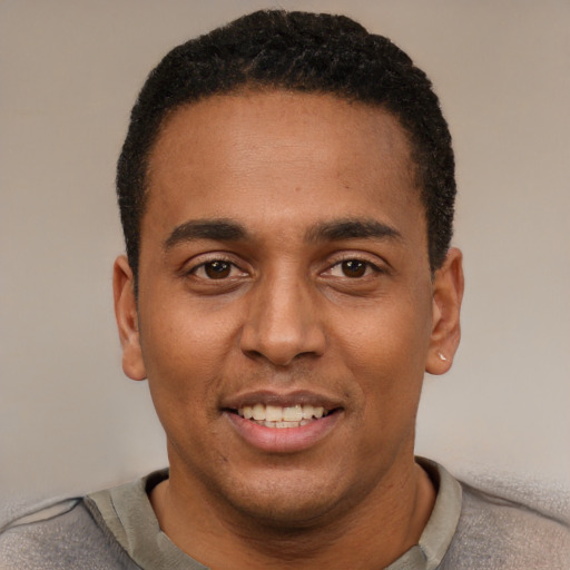 Joyful black young-adult male with short  black hair and brown eyes