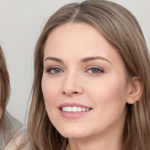 Joyful white young-adult female with long  brown hair and grey eyes