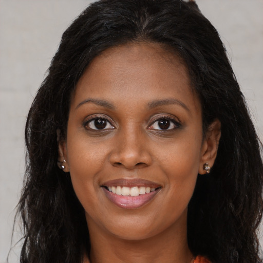 Joyful black young-adult female with long  brown hair and brown eyes