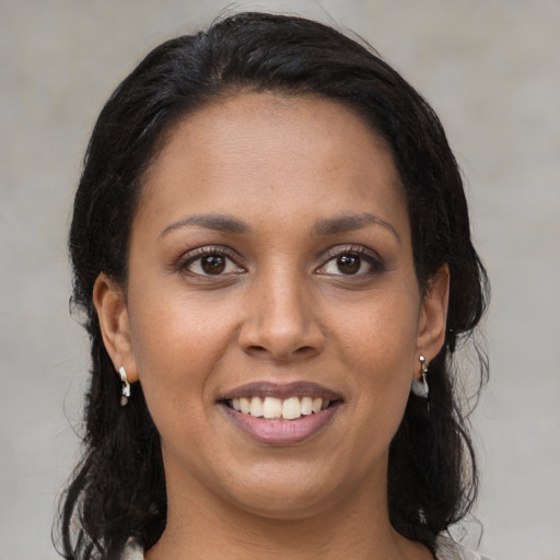 Joyful black young-adult female with long  brown hair and brown eyes