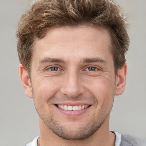 Joyful white young-adult male with short  brown hair and grey eyes