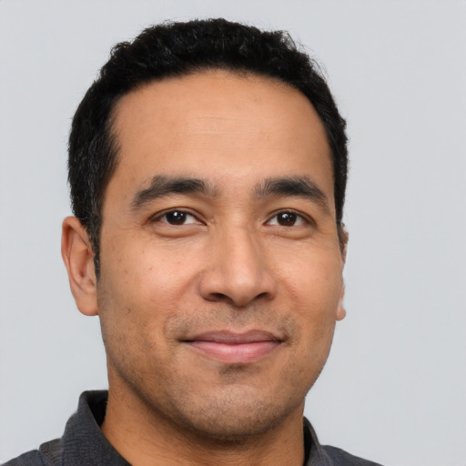 Joyful latino young-adult male with short  black hair and brown eyes