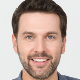 Joyful white young-adult male with short  brown hair and grey eyes