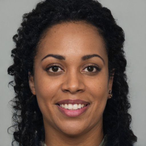 Joyful black young-adult female with long  black hair and brown eyes