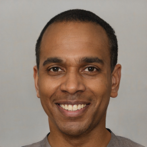 Joyful black adult male with short  black hair and brown eyes