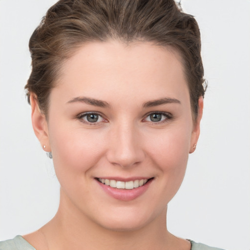 Joyful white young-adult female with short  brown hair and grey eyes