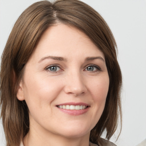 Joyful white young-adult female with medium  brown hair and grey eyes