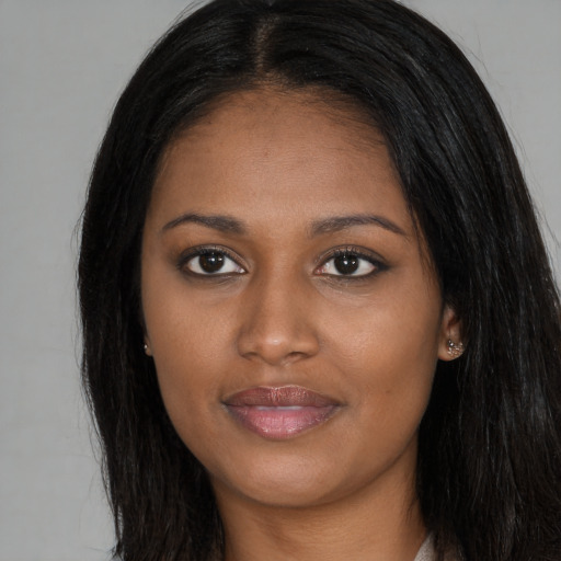 Joyful black young-adult female with long  brown hair and brown eyes