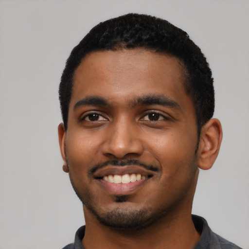 Joyful black young-adult male with short  black hair and brown eyes