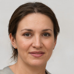 Joyful white young-adult female with medium  brown hair and grey eyes