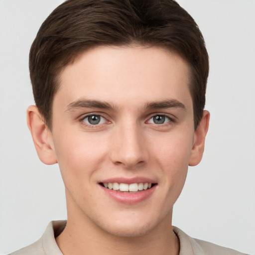 Joyful white young-adult male with short  brown hair and grey eyes