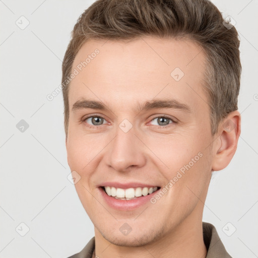 Joyful white young-adult male with short  brown hair and grey eyes