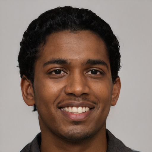 Joyful black young-adult male with short  black hair and brown eyes