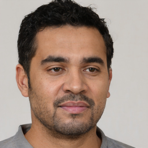 Joyful latino young-adult male with short  black hair and brown eyes