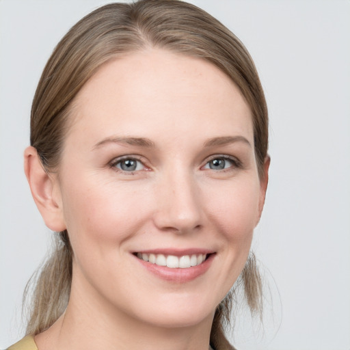 Joyful white young-adult female with medium  brown hair and grey eyes