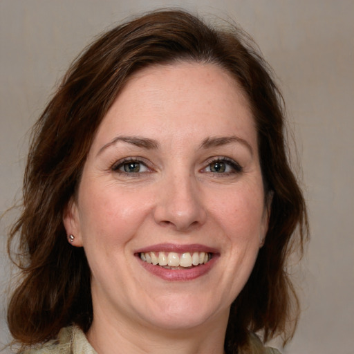 Joyful white adult female with medium  brown hair and blue eyes