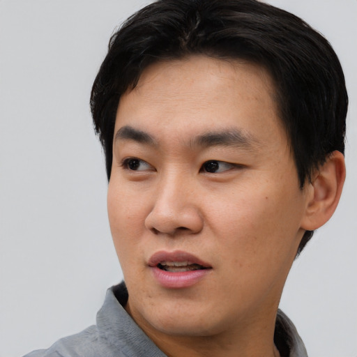 Joyful asian young-adult male with short  black hair and brown eyes