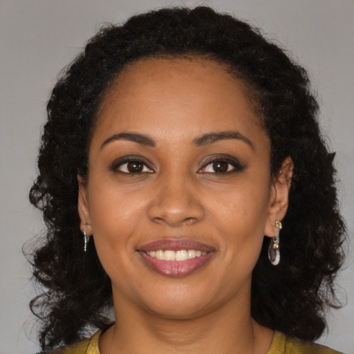 Joyful black young-adult female with long  brown hair and brown eyes