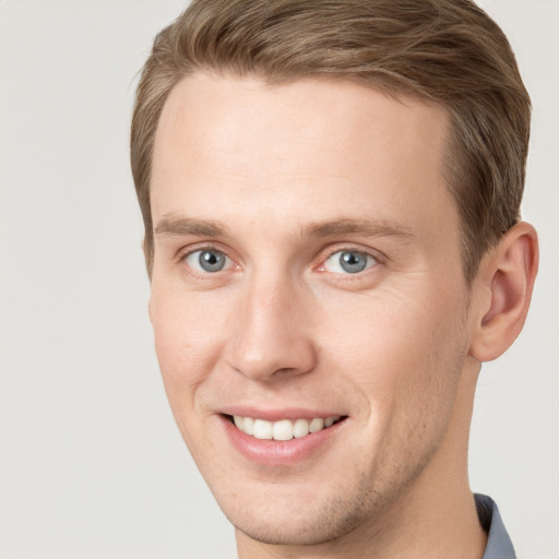 Joyful white young-adult male with short  brown hair and grey eyes