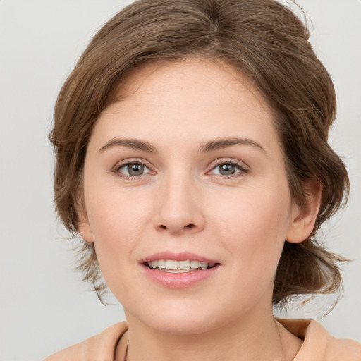 Joyful white young-adult female with medium  brown hair and grey eyes