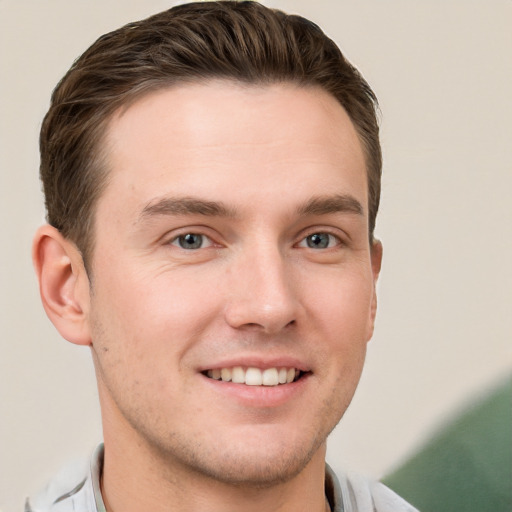 Joyful white young-adult male with short  brown hair and grey eyes