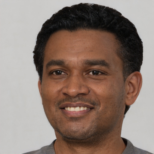 Joyful black young-adult male with short  black hair and brown eyes