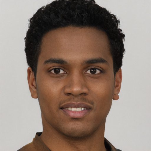 Joyful black young-adult male with short  black hair and brown eyes