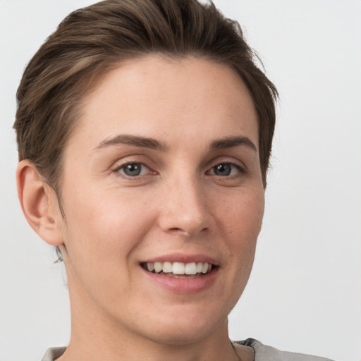 Joyful white young-adult female with short  brown hair and grey eyes