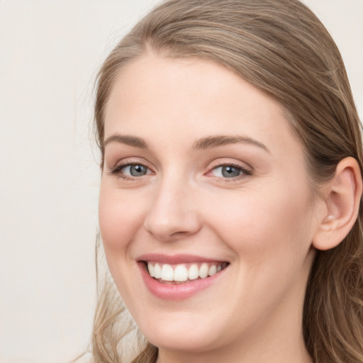 Joyful white young-adult female with long  brown hair and blue eyes