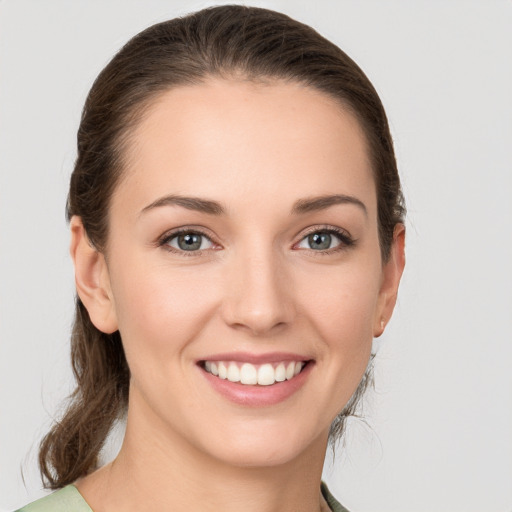 Joyful white young-adult female with medium  brown hair and grey eyes