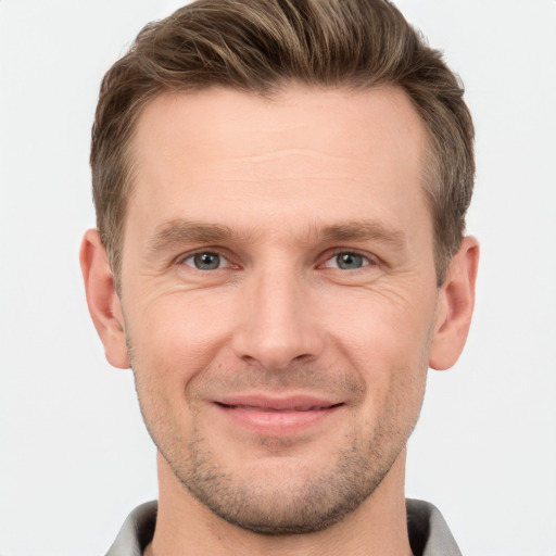 Joyful white young-adult male with short  brown hair and grey eyes