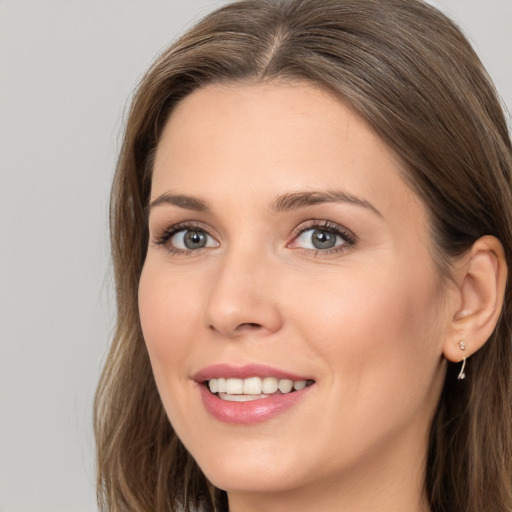 Joyful white young-adult female with long  brown hair and grey eyes