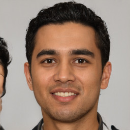 Joyful latino young-adult male with short  black hair and brown eyes