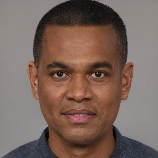 Joyful black young-adult male with short  brown hair and brown eyes