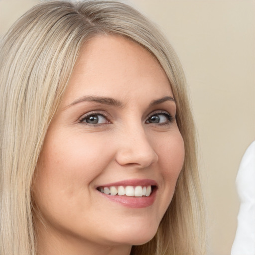 Joyful white young-adult female with long  blond hair and brown eyes