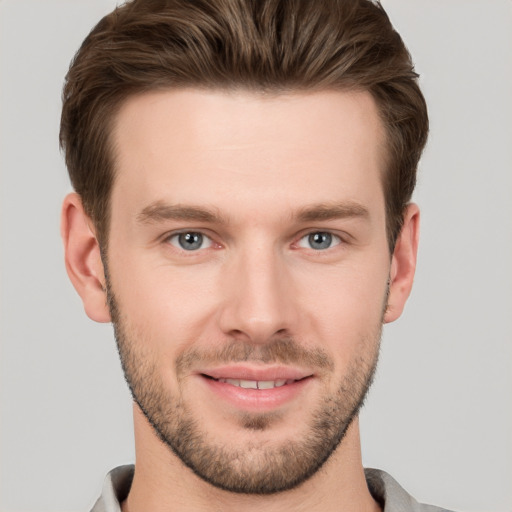 Joyful white young-adult male with short  brown hair and grey eyes