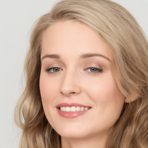 Joyful white young-adult female with long  brown hair and blue eyes