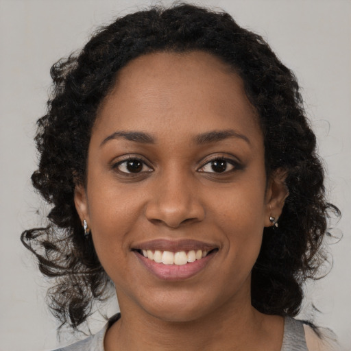 Joyful black young-adult female with long  black hair and brown eyes