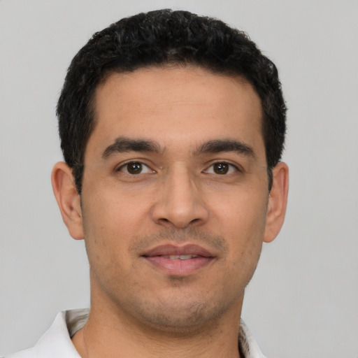 Joyful latino young-adult male with short  black hair and brown eyes