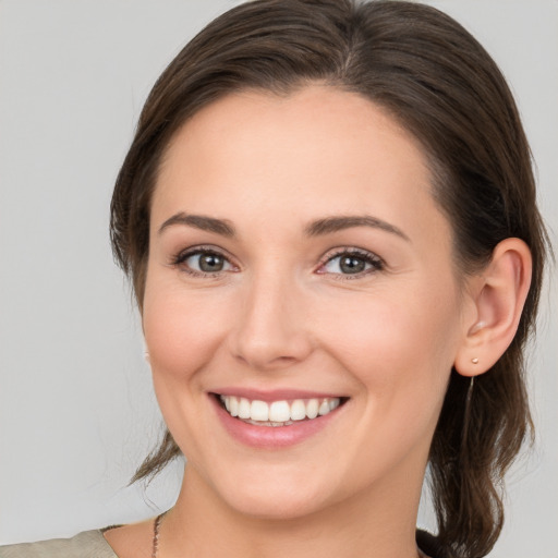 Joyful white young-adult female with medium  brown hair and grey eyes