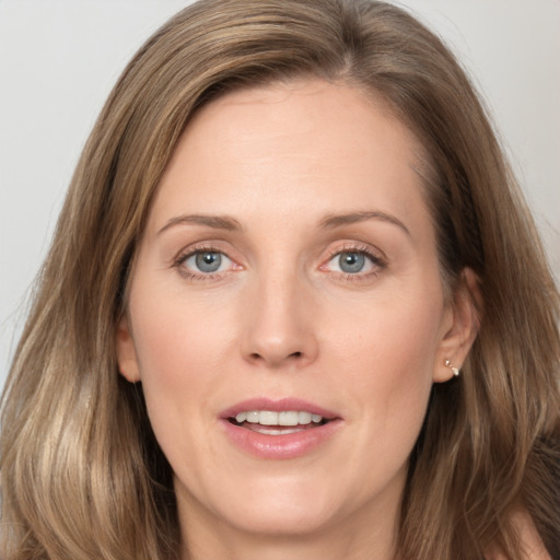 Joyful white adult female with long  brown hair and grey eyes