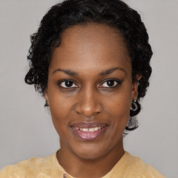 Joyful black young-adult female with short  black hair and brown eyes