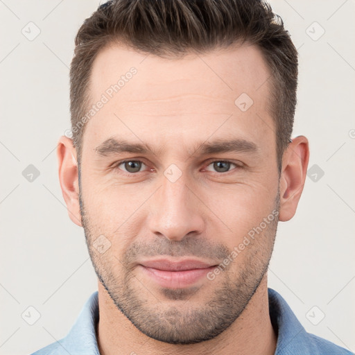 Joyful white young-adult male with short  brown hair and grey eyes