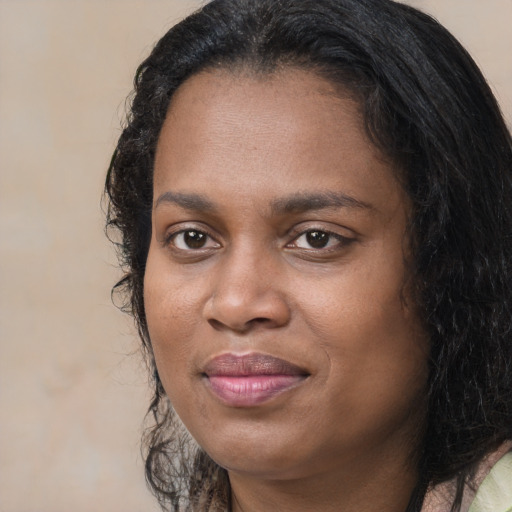 Joyful black adult female with long  brown hair and brown eyes