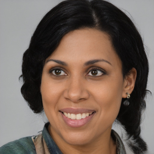 Joyful latino adult female with medium  black hair and brown eyes