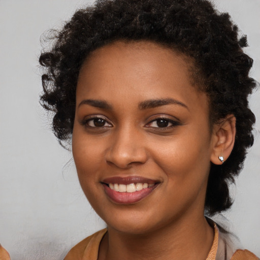 Joyful black young-adult female with long  brown hair and brown eyes